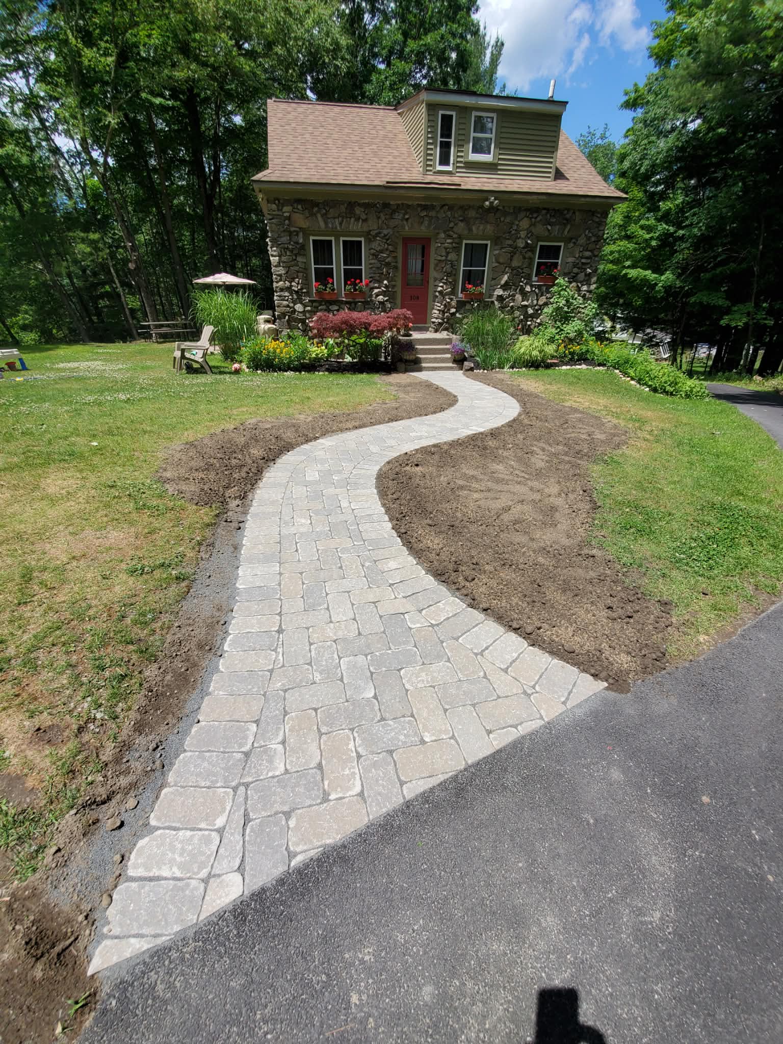 Finished curved paver walkway around stone cottage