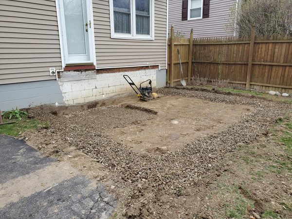 Bare backyard being excavated with plate compactor