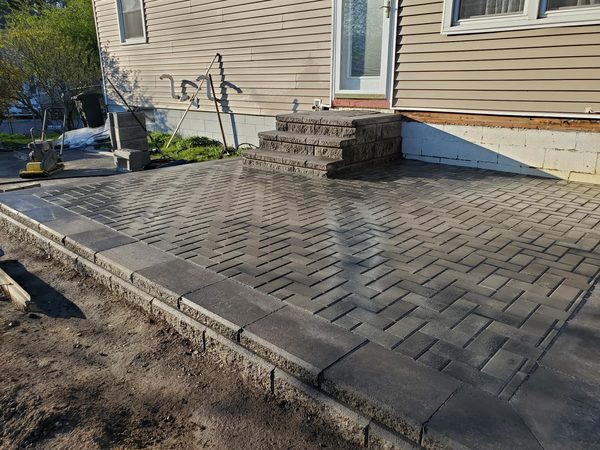 Completed backyard patio with herringbone pavers and block steps