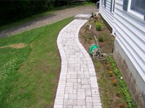Side walkway with curved pavers and flower bed border